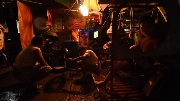 Two men repair a tyre in one of the alleys of Tondo district in Manila.
