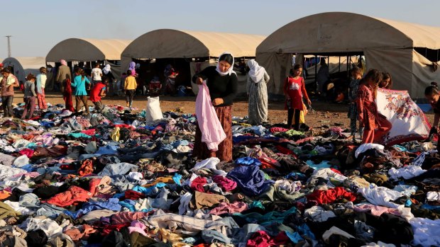 August 2014: displaced Iraqis from the Yazidi community look for clothes to wear among items provided by a charity organisation at the Nowruz camp in Dayrik, also known as al-Malikiya, Syria.  