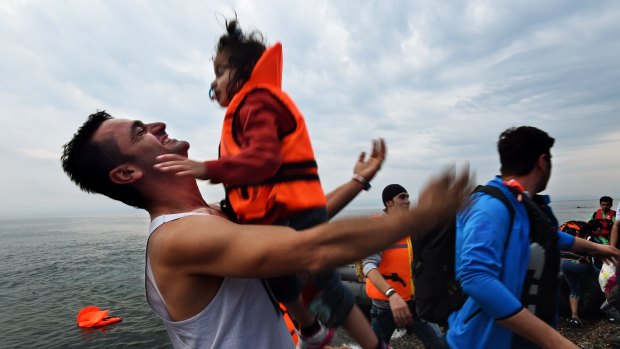 A Syrian man throws his daughter into the air with joy moments after arriving by rubber dinghy with approximately 45 refugees at Lesbos after a three hour journey from Turkey in September. 