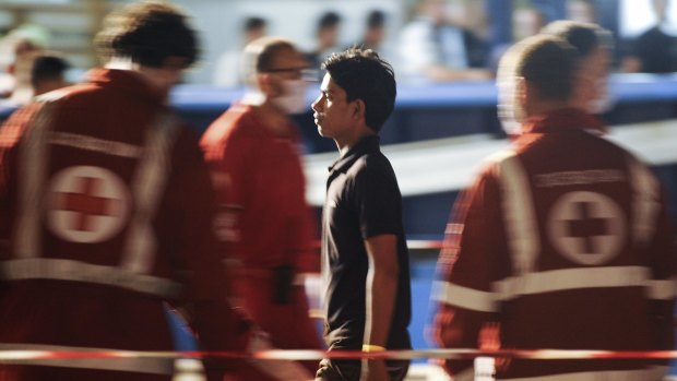 A migrant walks past Red Cross personnel after disembarking from the Swedish vessel Poseidon in the Sicilian harbour of Palermo, Italy, on Thursday.