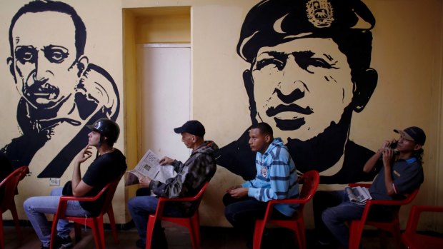 Voters wait to cast their ballots next murals of Venezuelan independence hero Ezequiel Zamora, left, and late Venezuelan President Hugo Chavez at a polling station in Caracas, Venezuela. 