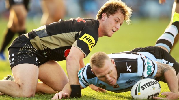 Matt Moylan of the Panthers loses the ball after a heavy hit by by Luke Lewis of the Sharks.