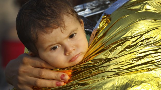 A Syrian refugee child is covered by thermal blanket in Kos following a rescue mission on Monday.