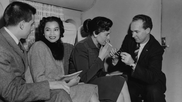 乘客享受放松的烟雾在越洋航空波音377在1950年代中期同温层飞机。