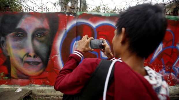 A man takes pictures of graffiti congratulating Myanmar opposition leader Aung San Suu Kyi and her party's victory in her seat on Wednesday.