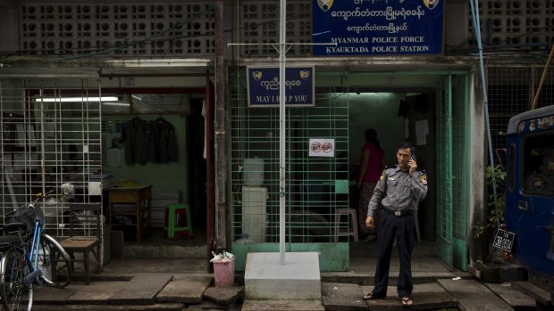 A police officer talks on the phone outside a police station in Yangon on Tuesday. The police force falls under the Home Affairs Ministry, which will remain under the control of the military. 
