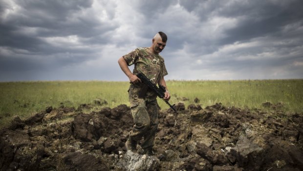 A Ukrainian serviceman investigates a crater left by a Grad rocket in the village of Toshkivka, Luhansk region, eastern Ukraine.