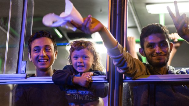 Migrants celebrate after boarding a bus bound for Austria.