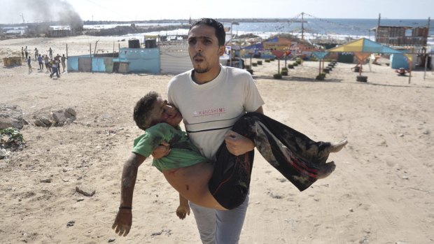 A Palestinian man carries one of the boys killed in the Gaza beach attack on July 16, 2014.  