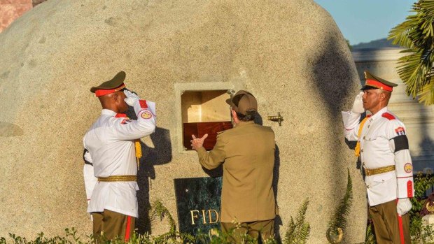 Cuban President Raul Castro places the ashes of his older brother Fidel Castro into a niche in his tomb at the Santa Ifigenia cemetery in Santiago, Cuba.