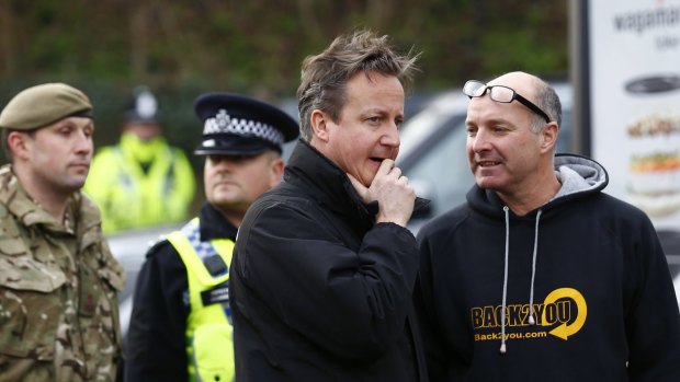 British Prime Minister David Cameron, centre, sent hundreds more troops into northern England on Sunday to help exhausted residents and emergency workers fight rising river waters.