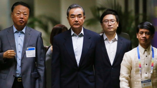 Chinese Foreign Minister Wang Yi, centre, is escorted by Chinese Ambassador to the Philippines Zhao Jianhua, left, on at the ASEAN meeting on Saturday.