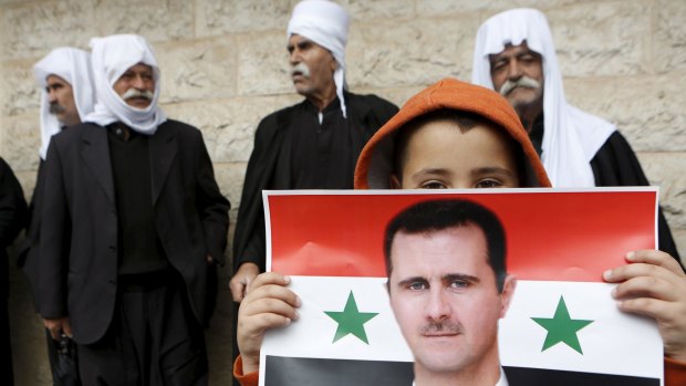 A boy from the Druze community holds a Syrian flag with the image of President Bashar al-Assad during a 2013 rally in the Druze village of Buqata on the Israeli-occupied Golan Heights.