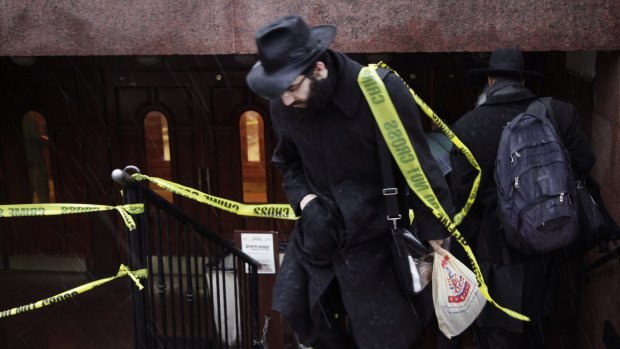 A member of the Chabad community walks through crime scene tape at the movement's headquarters in Crown Heights, Brooklyn. 