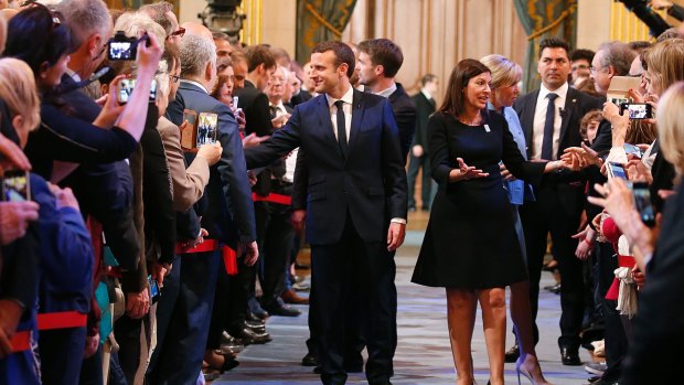French President Emmanuel Macron and Paris Mayor Anne Hidalgo, right, greet guests on Sunday.