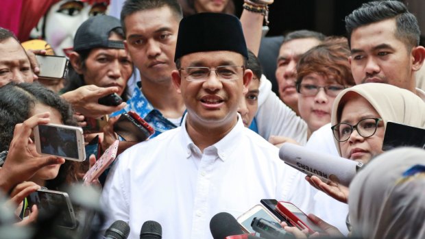 Anies Baswedan, centre, is mobbed by the press after casting his vote.