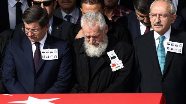 Turkish Prime Minister Ahmet Davutoglu, left, opposition leader Kemal Kilicdaroglu, right,  and a family member of a victim attend funeral prayers for victims of Wednesday's explosion in Ankara.