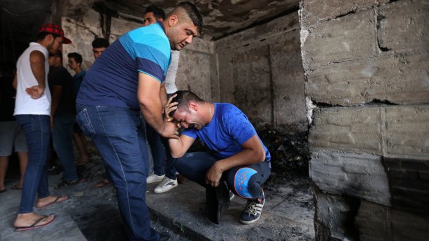 Iraqi men grieve at the scene of the deadly suicide bombing in Baghdad.