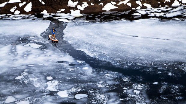 Jake Sims' spectacular photo of his friend paddle-boarding on an icy alpine lake.