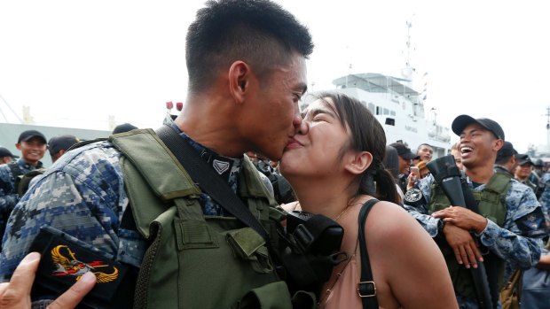 Philippine Coast Guard SN2 Dan Mark Torres  kisses his girlfriend Denise Guttierez, as his group are given a heroes' welcome with flowers and promotion in Manila.