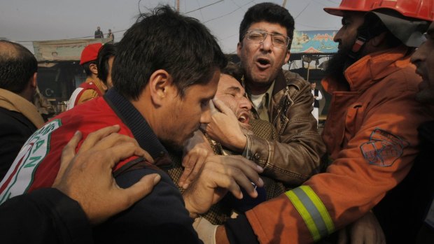People comfort a man who lost a family member in a suicide attack, in Peshawar, Pakistan.