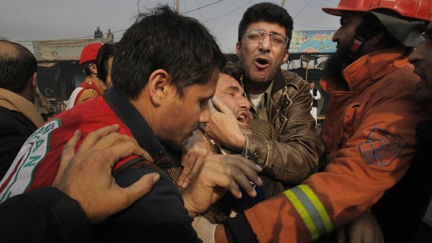 People comfort a man who lost a family member in a suicide attack, in Peshawar, Pakistan.