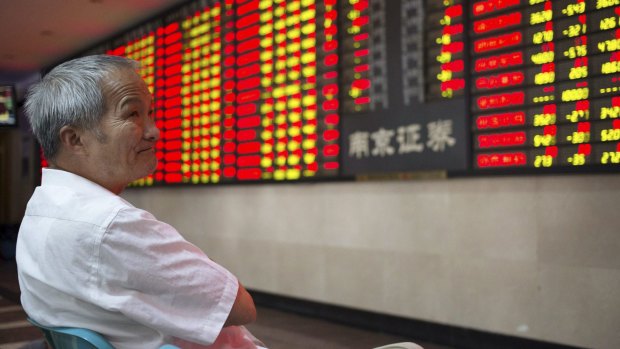 An investor closely watches  an electronic board showing stock information at a brokerage house in Nanjing, Jiangsu province.