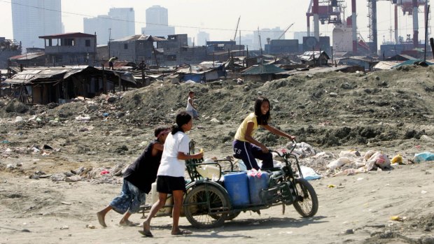 A girl struggles to pedal her three-wheeled bike loaded with plastic containers full of water in the squatter district of Baseco in Manila in 2006.