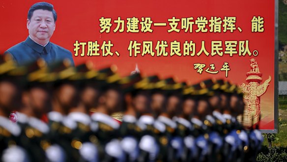 Soldiers of China's People's Liberation Army march under the gaze of a photo of President Xi Jinping.