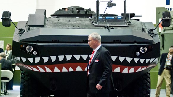 A businessman walks past an Iveco vehicle during the 2013 edition of the Defence & Security Equipment International arms fair  in London.