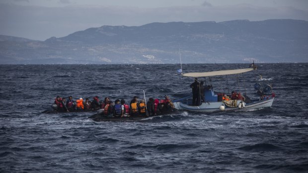 Two dinghies carrying migrants and refugees from nearby Turkey are tugged to safety by a local fishing boat near the village of Skala, Lesbos, on Sunday.