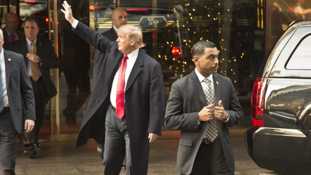 Republican presidential candidate Donald Trump waves to onlookers as he leaves Trump Towers surrounded by security.
