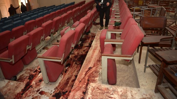 A Pakistani journalist takes a photo of the bloodied floor in the ceremony hall where many children were gunned down.