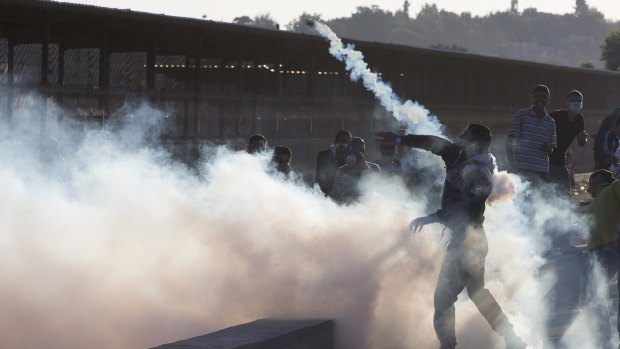 A Palestinian protester throws a tear gas canister away from demonstrators during clashes with Israeli soldiers securing the entrance of the Erez border crossing between the Gaza Strip and Israel on Friday.