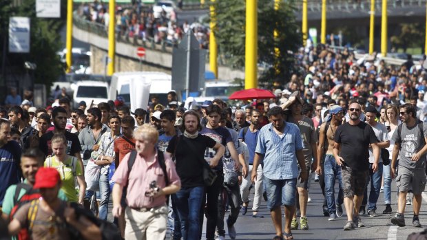 A defiant march to Germany: Migrants walk along the Hegyalja Street in Budapest on Thursday before Hungary set up bus transport to take them.