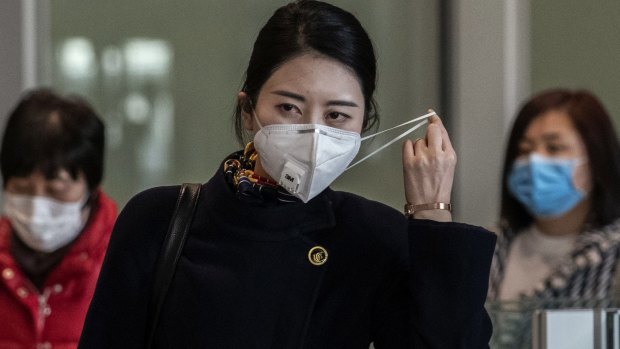 A flight attendant adjusts her mask after disembarking from a flight in Beijing.