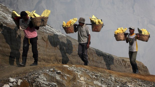 Miners carry baskets of sulphur in Indonesia.