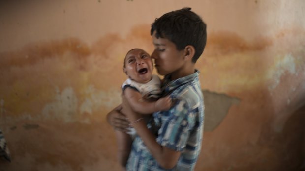 Ten-year-old Elison nurses his two-month-old brother Jose Wesley at their house in Poco Fundo, Pernambuco state, Brazil.