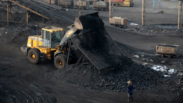 A worker watches a bulldozer unload coal at a mine in central China's Anhui province.
