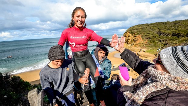Summer being carried by her friend, Zac (left) and dad, Mark after winning the Women's Open title at the Australian Indigenous Surfing Titles at Bells Beach. 