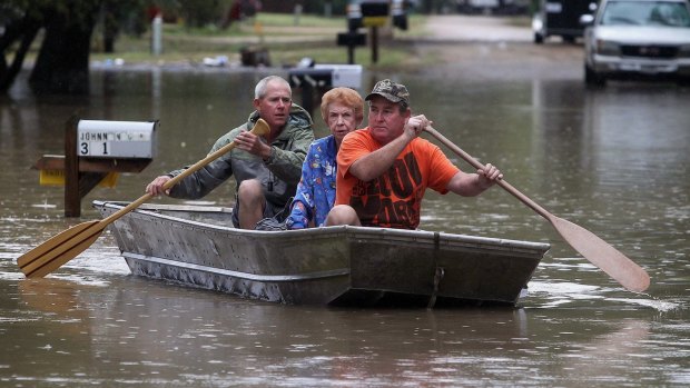 J.B. Neckar, right, and his brother Johnny paddle their mother Gelene Neckar from her flooded home near Downsville, Texas.