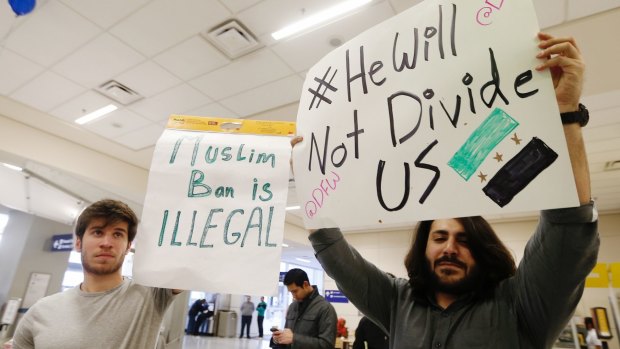 Southern Methodist University student Osama al-Olabi, left, and his brother, a SMU graduate, Tarek al-Olabi, right, demonstrate against the order at Dallas Fort Worth Airport.