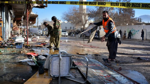 Pakistani police and rescue workers examine the site of suicide bombing that killed at least 15 in Quetta, Pakistan on Wednesday.