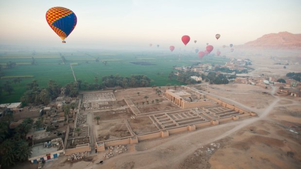 Hot-air balloons near the limestone mountains of the Valley of the Kings.