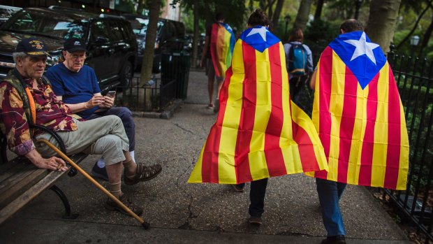 Two men watch pro-independence supporters passing by as they gather in support for the secession of the Catalonia region from Spain outside the United Nations headquarters in New York on Wednesday.