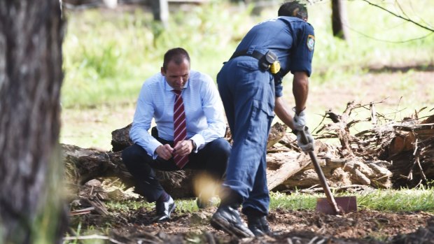 Police officers search the grounds of the semi-rural property in Bonny Hills.