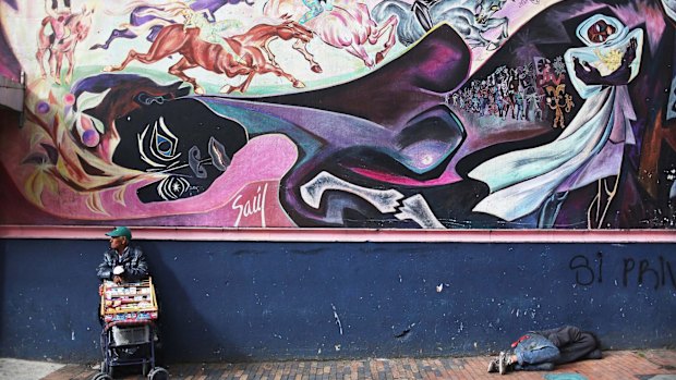 A vendor looks on as a man sleeps beneath graffiti during the referendum in Bogota, Colombia. 