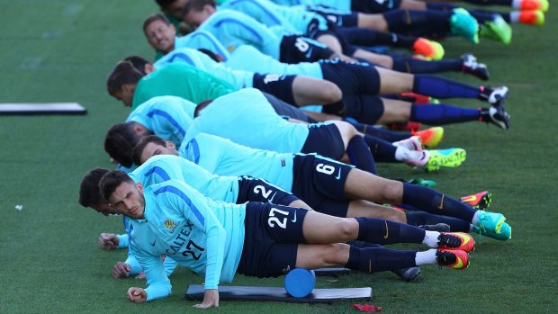 All lined up: The Socceroos stretch during a training session at nib Stadium in Perth.