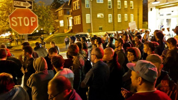A crowd gathers near where a man was fatally shot by an off-duty St. Louis police officer 