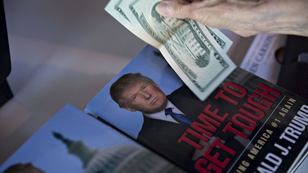 A guest pays for books near a book by Donald Trump at the summit in Ames, Iowa, on Saturday.